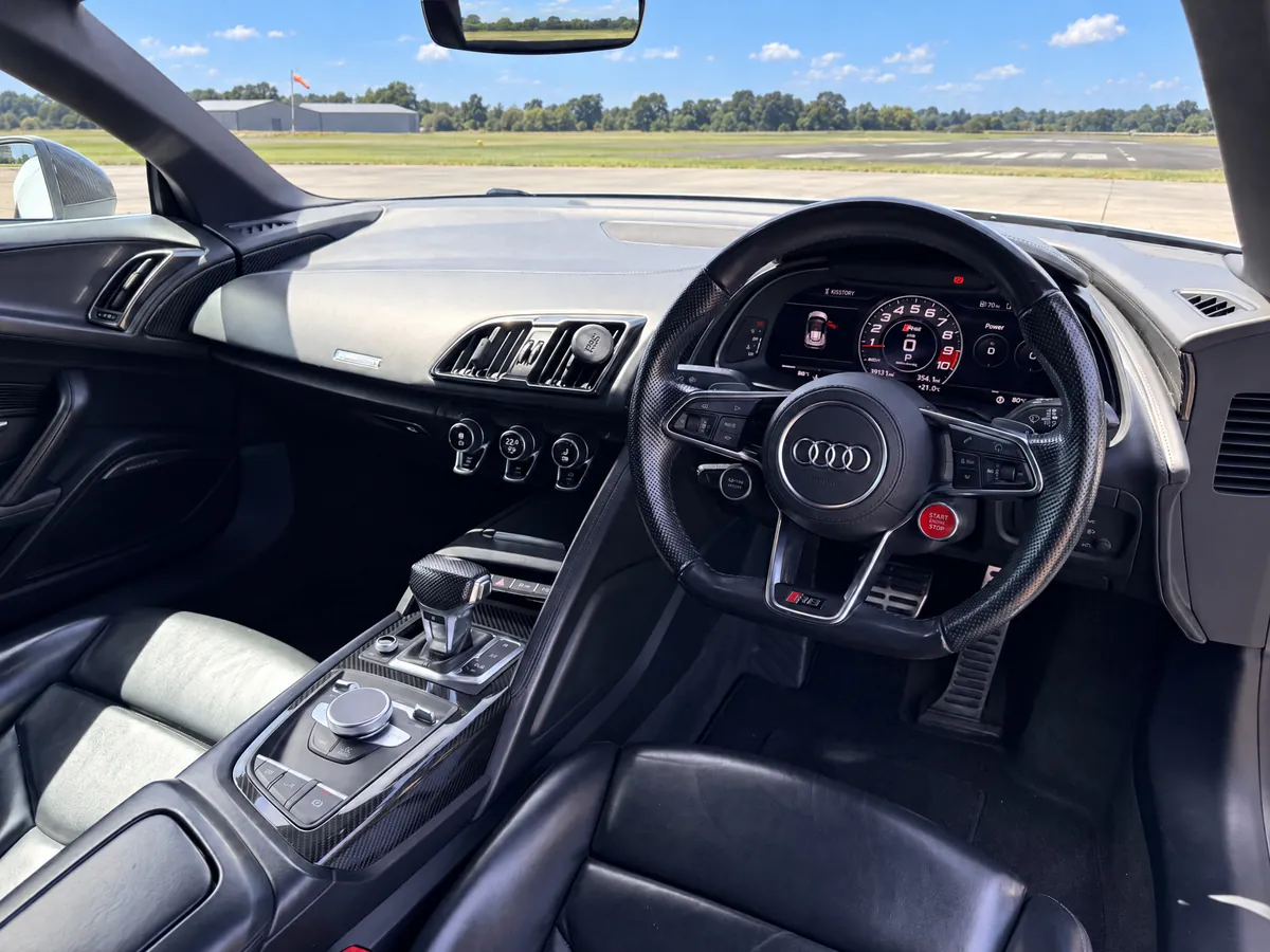 The driver's view inside the Audi R8 Spyder — flat-bottomed steering wheel, virtual cockpit display and carbon centre console