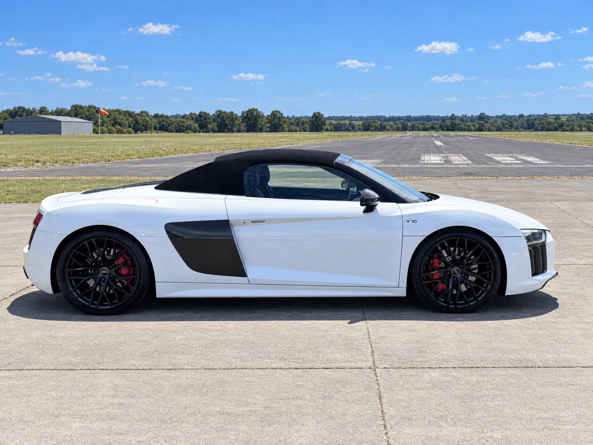 Side profile of the white Audi R8 V10 Spyder for hire in Norwich — carbon side blade, gloss-black alloys and red brake calipers